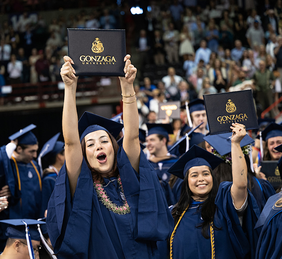 Man leans against brick wall with cherry blossom tree behind it.